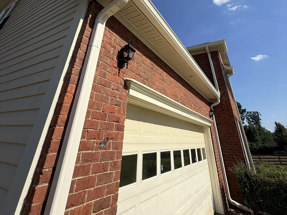 Crew member soft washing the vinyl siding of a two-story Augusta home from the ground