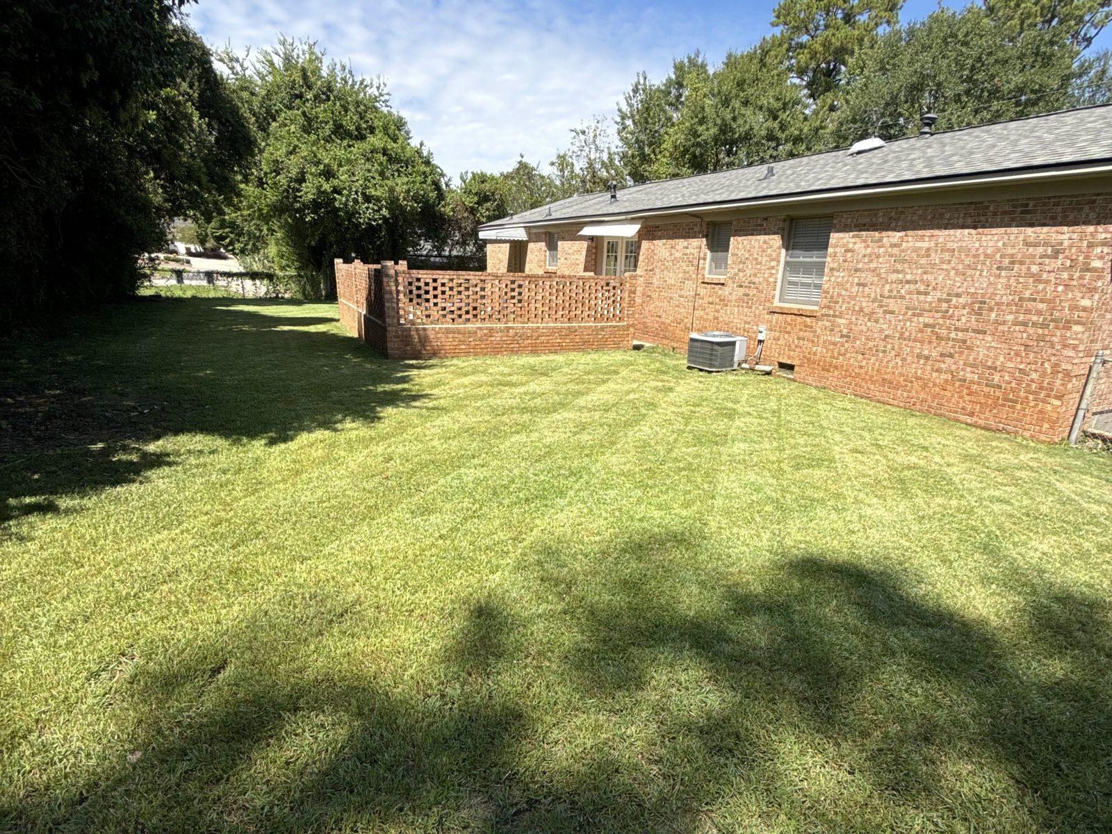 Freshly mowed backyard behind a brick ranch home