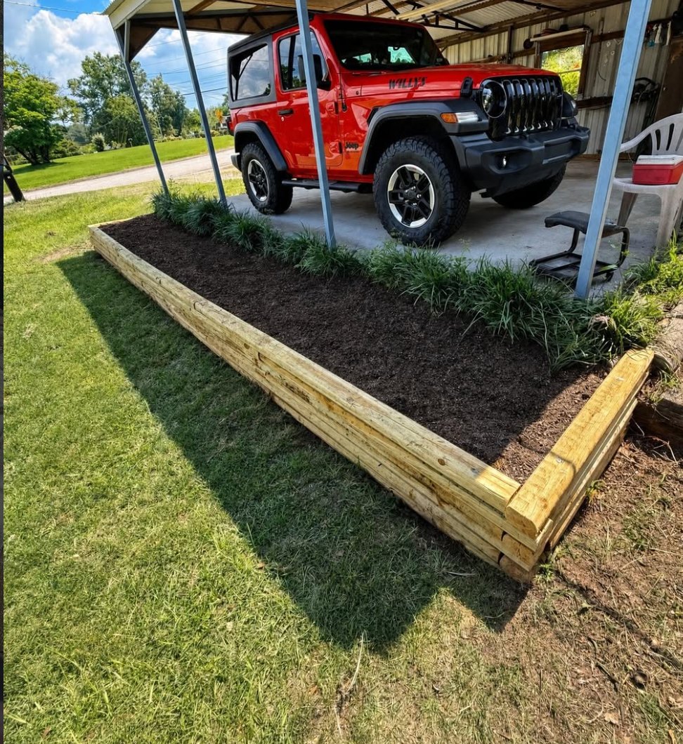 Timber-bordered raised bed with fresh mulch by Anything Exterior